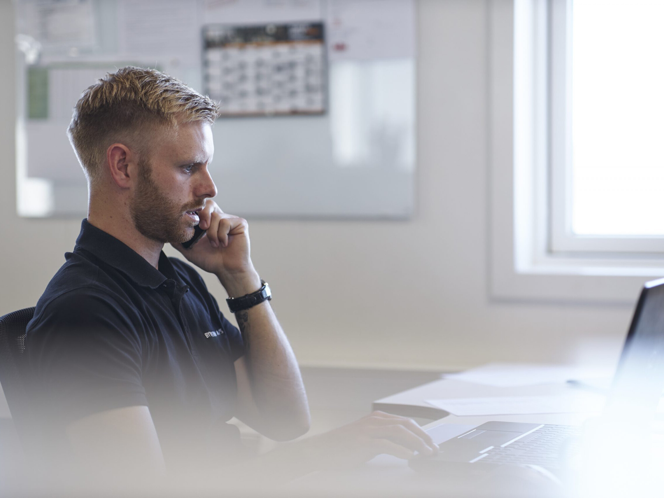 Medarbejder snakker i telefon p&aring; kontor